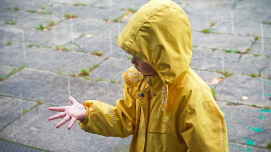 child in raincoat looking at rain