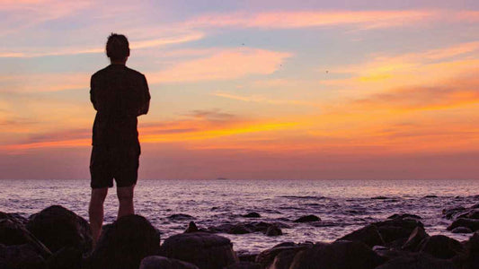 man watching clouds on rocky shore