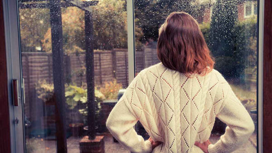 woman looking out window at rain