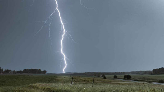 lightning over a farm field at dusk